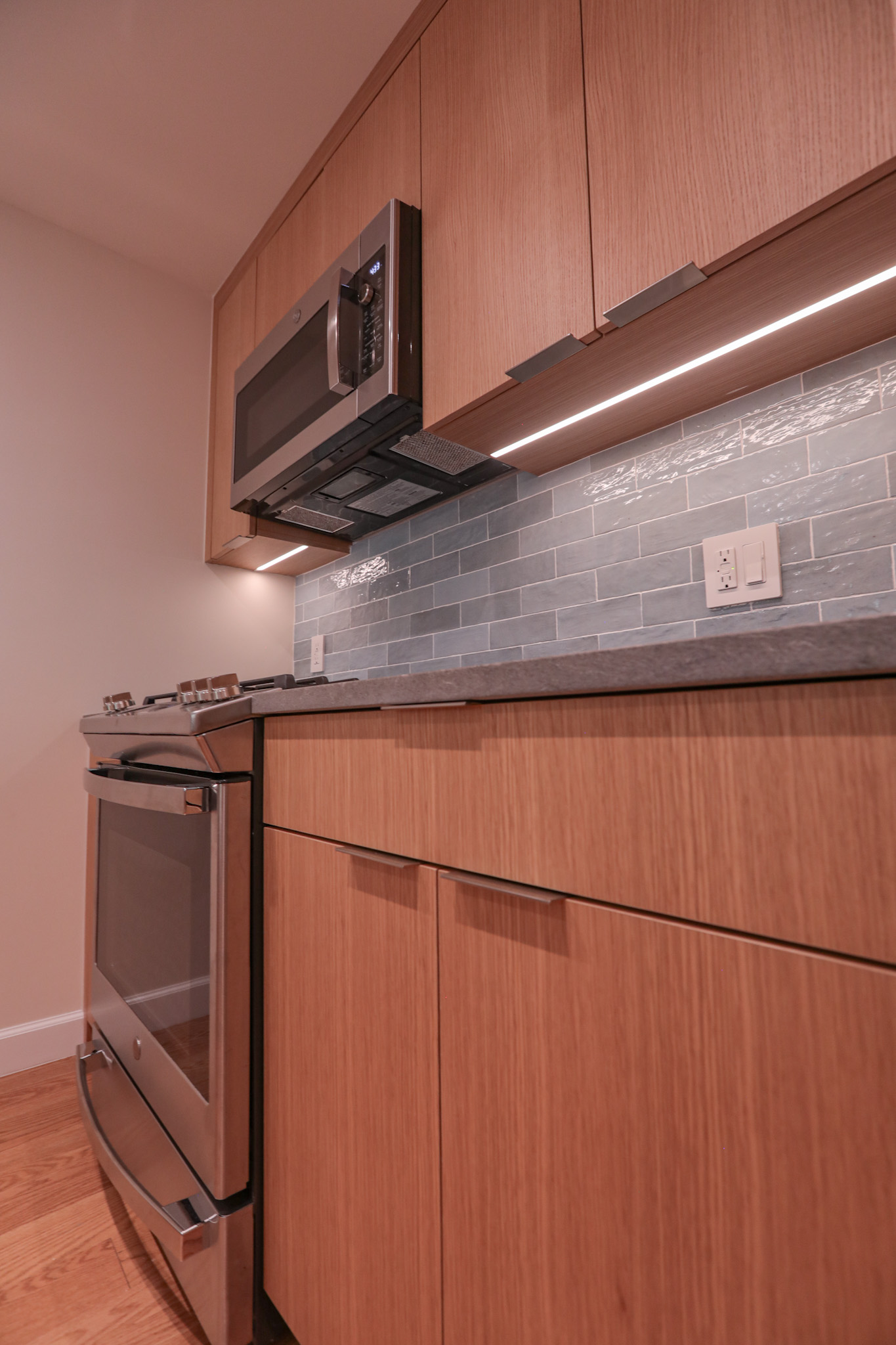 Kitchen detail — oak cabinets, grey subway tile, under-cabinet lighting